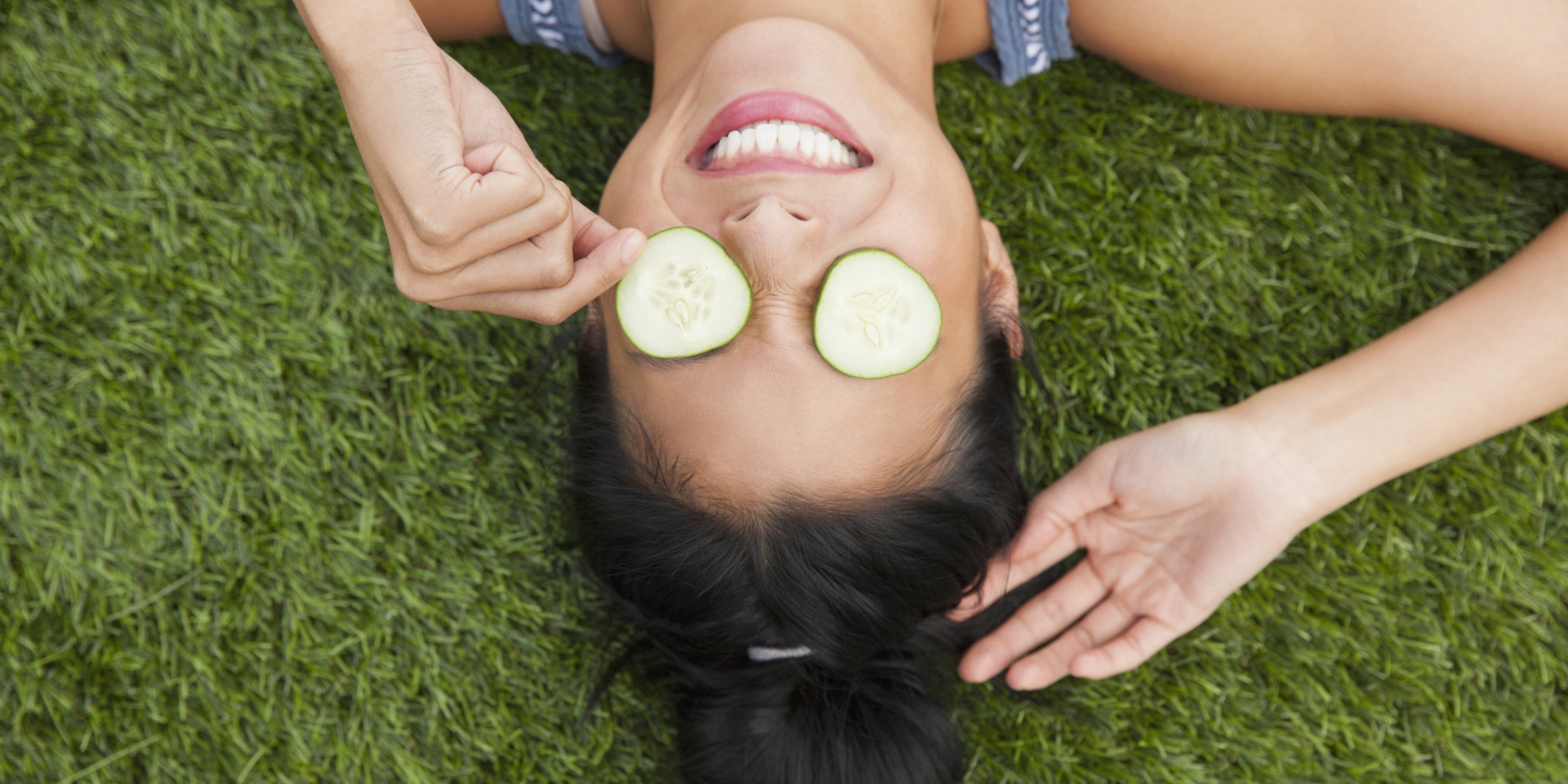 Chinese woman with cucumbers on eyes laying in grass